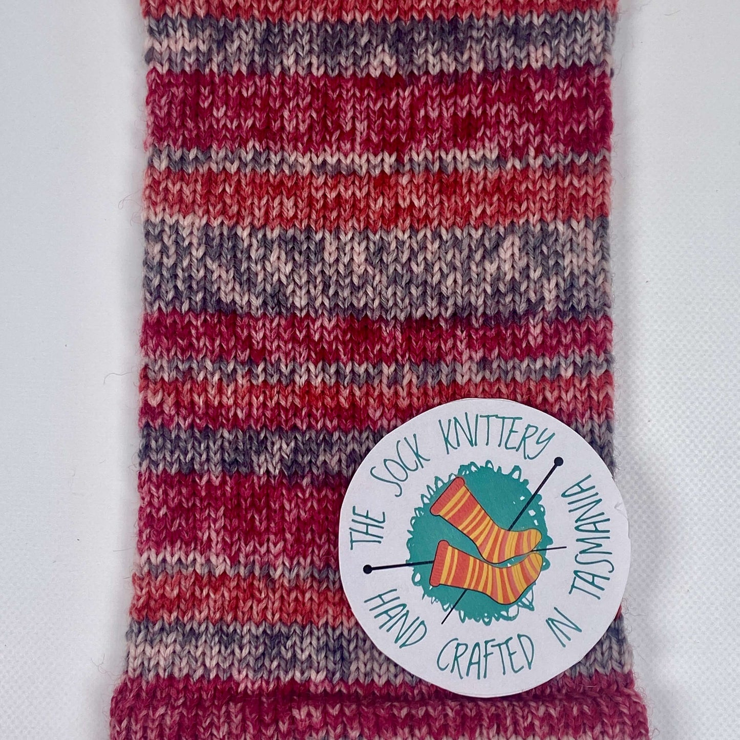 sample of knitted sock yarn showing speckled striped in red, orange, grey and cream - The Sock Knittery