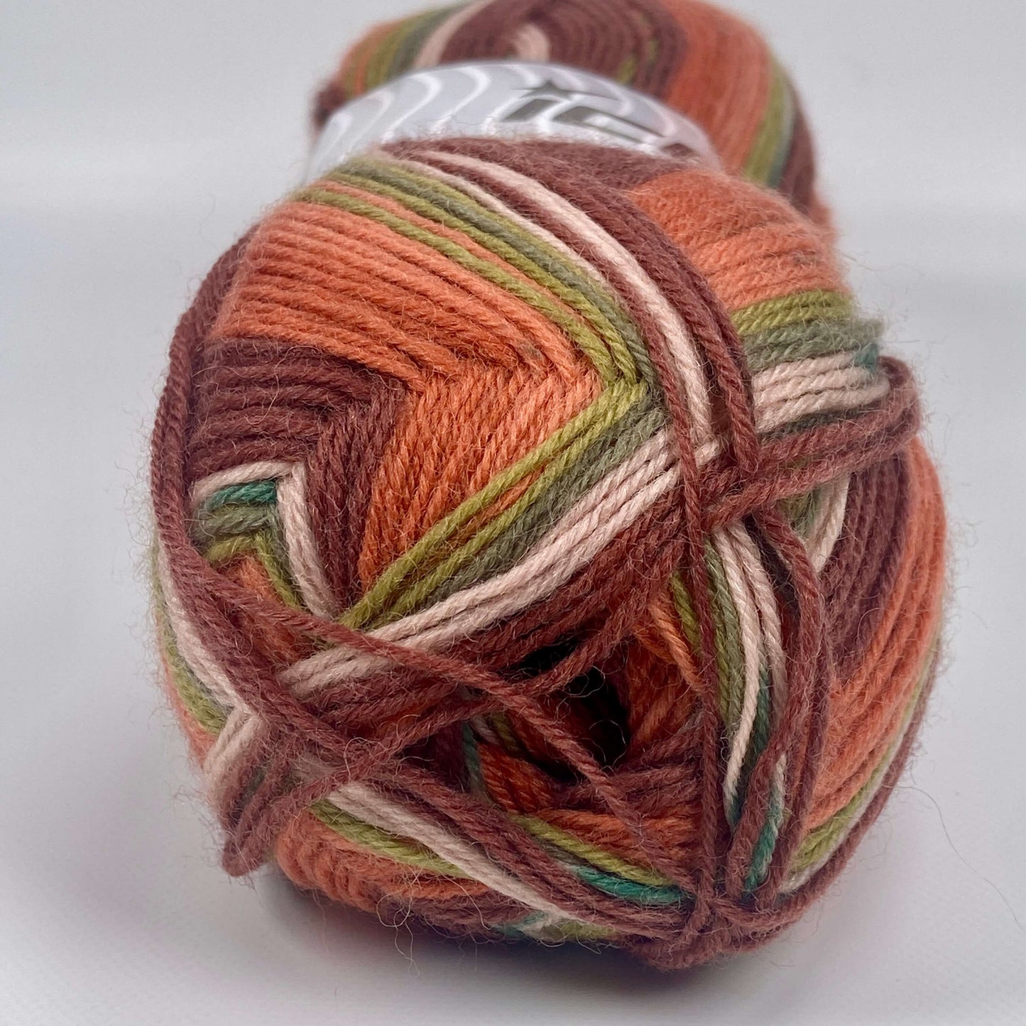 ball of sock yarn by Ice Yarns in copper , green shades and cream - The Sock Knittery